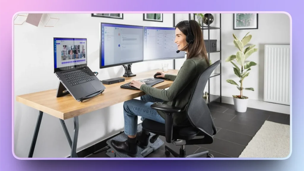 Professional woman wearing headset working at desk with laptop and dual monitors in modern office.