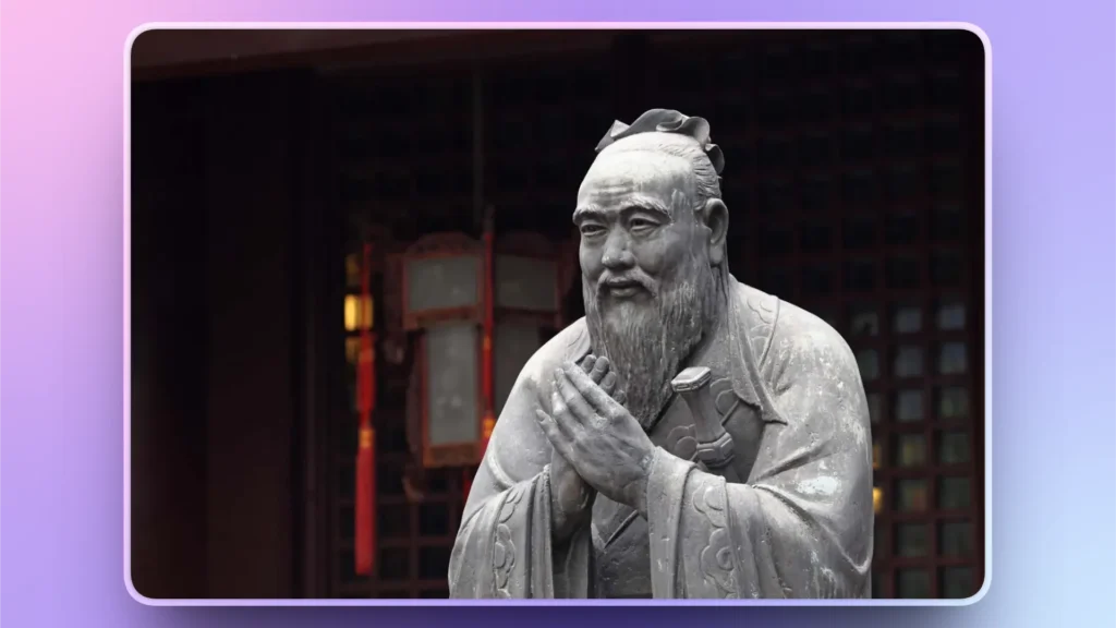 Stone statue of an elderly man with traditional robes and a long beard, hands clasped.
