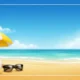 Beach scene with yellow and white umbrella, colorful beach ball, black sunglasses, ocean, and blue sky.