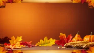 Autumnal arrangement with corn, wheat, mini pumpkins, and colorful fall leaves on wooden surface.
