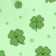 Pattern of green four-leaf clovers with smiling faces on a light green background with dots.