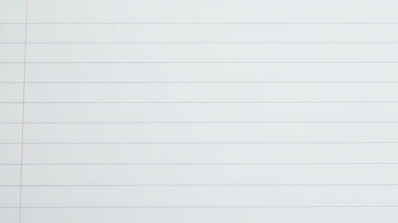 Close-up of a blank white lined notebook page with a red vertical margin line.