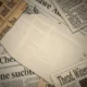 Close-up of overlapping vintage newspapers with partially visible text and yellowed paper.
