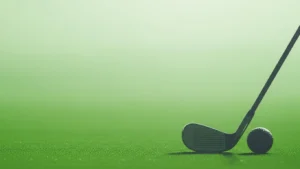 Golf club positioned next to a golf ball on a green, blurred background.