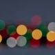 Blurred multicolored circular lights against a dark background, creating a festive bokeh effect.