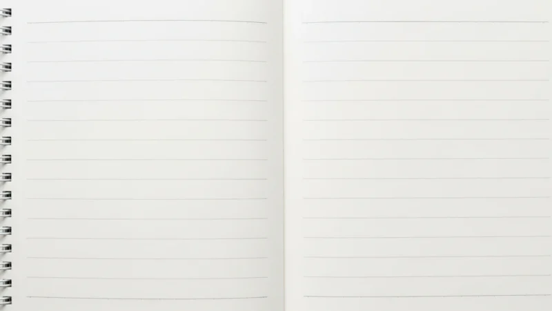 Open spiral-bound notebook with blank white lined pages on a neutral background.