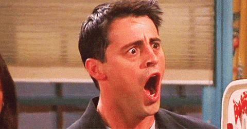 Man with dark hair wearing a black jacket, mouth open in shocked expression.