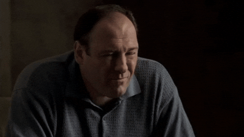 Middle-aged man with dark hair wearing a blue patterned shirt, appearing contemplative.