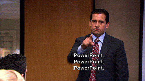 Man in dark suit and red patterned tie pointing, with white text "PowerPoint. PowerPoint. PowerPoint." displayed.