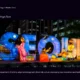 Illuminated lantern display spelling "SEOUL" with traditional Korean figures and modern city buildings at night.