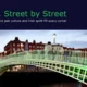 Evening view of Ha'penny Bridge in Dublin with red brick buildings and street lamps.