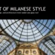 Glass dome roof with intricate iron framework above ornate Milanese architecture and frescoes.