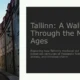 Cobblestone street in Tallinn's medieval old town with historic buildings and a pointed tower.