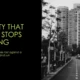 Black and white photograph of a modern city street with high-rise buildings and parked cars.